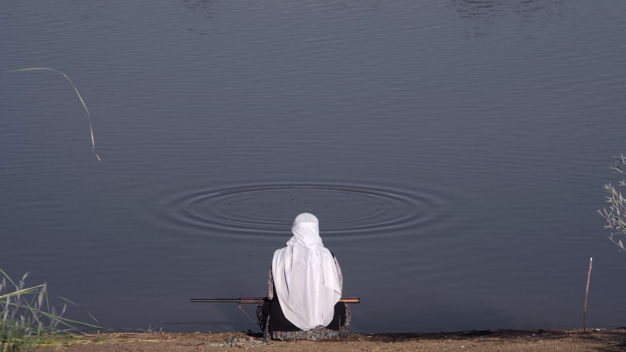 a woman sitting looking at a body of water